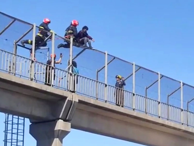 joven subido a lo más alto del puente peatonal de la autopista