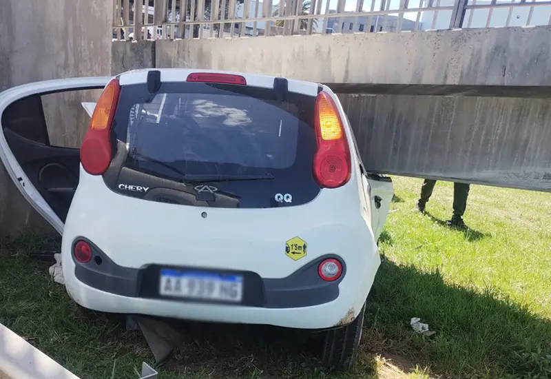 La parte trasera del vehículo entre la contención metálica de la autopista y el puente peatonal