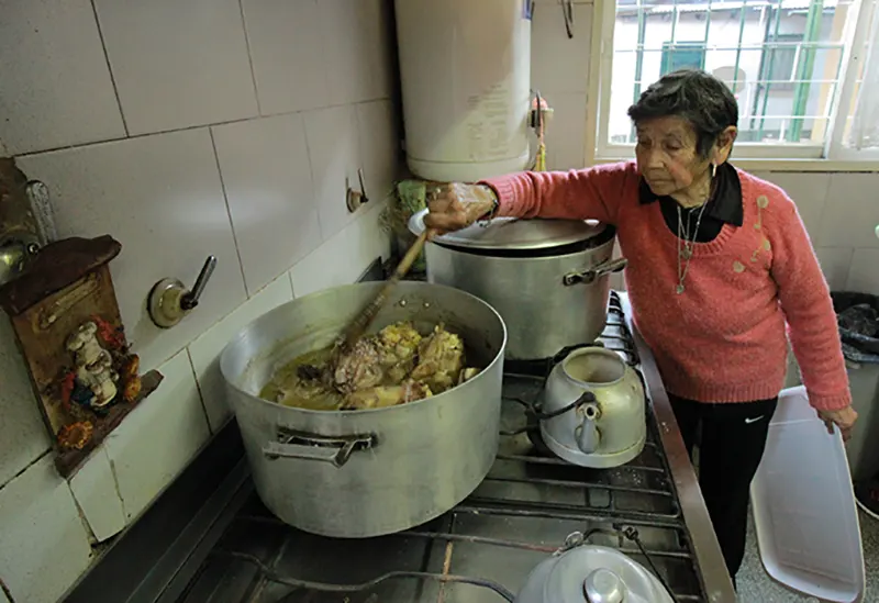 Dionisia Sequeira revolviendo una gran cacerola en la cocina del comedor