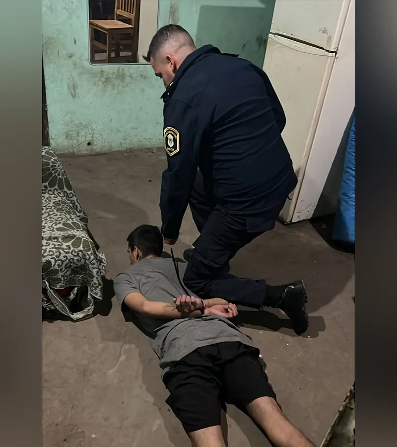 un detenido contra el piso con un policía sosteniéndolo