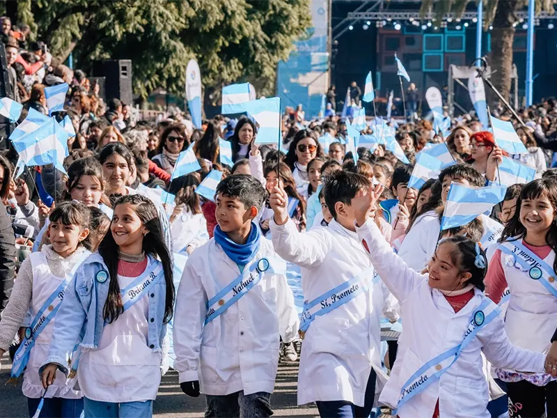 alumnos desfilan por el boulevard de garín haciendo flamear banderas argentinas