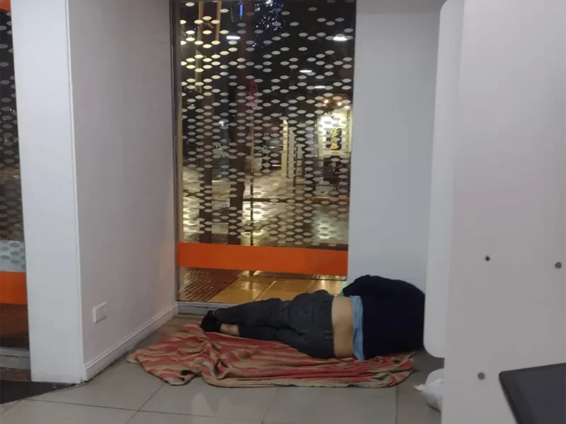 un hombre durmiendo en el sector de cajeros del Banco Galicia