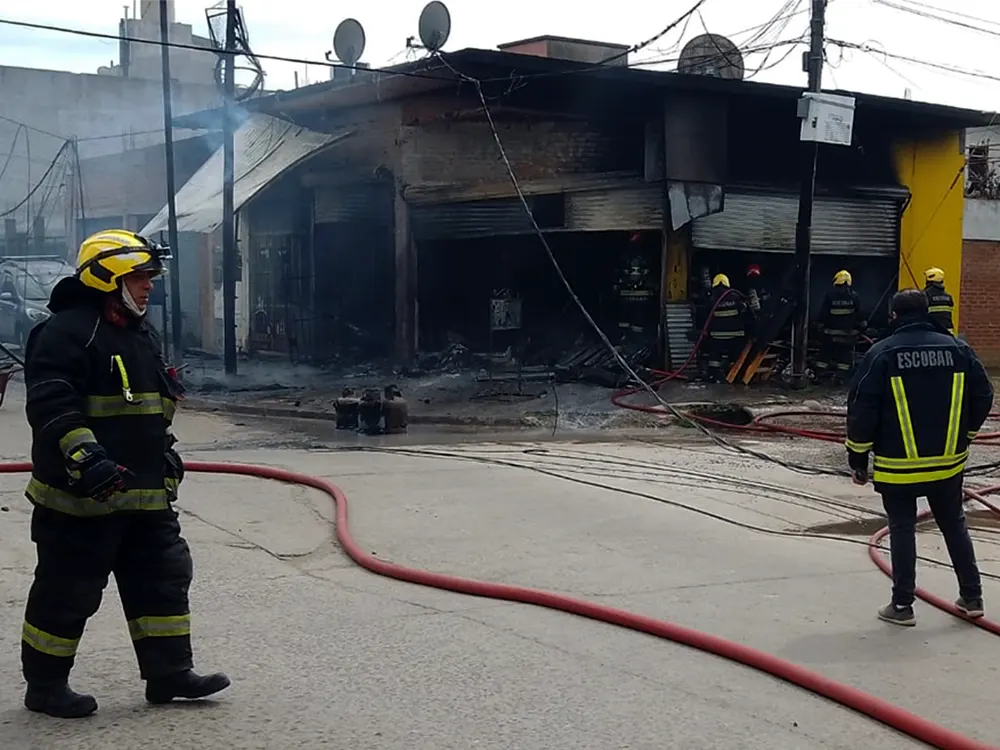 bomberos contemplan el comercio incenciado tras apagar las llamas