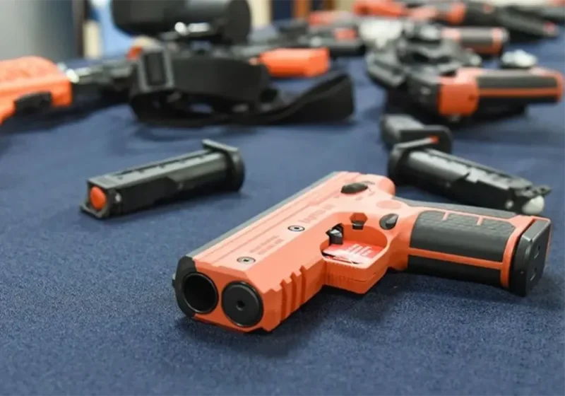 pistolas no letales Byrna sobre una mesa con mantel azul