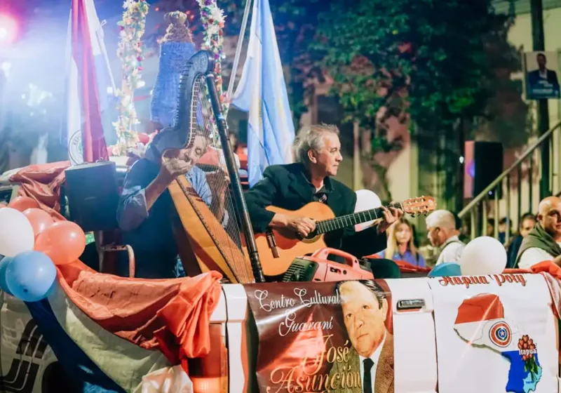 Grupo musical tocando guitarra y arpa en la carroza de la colectividad paraguaya