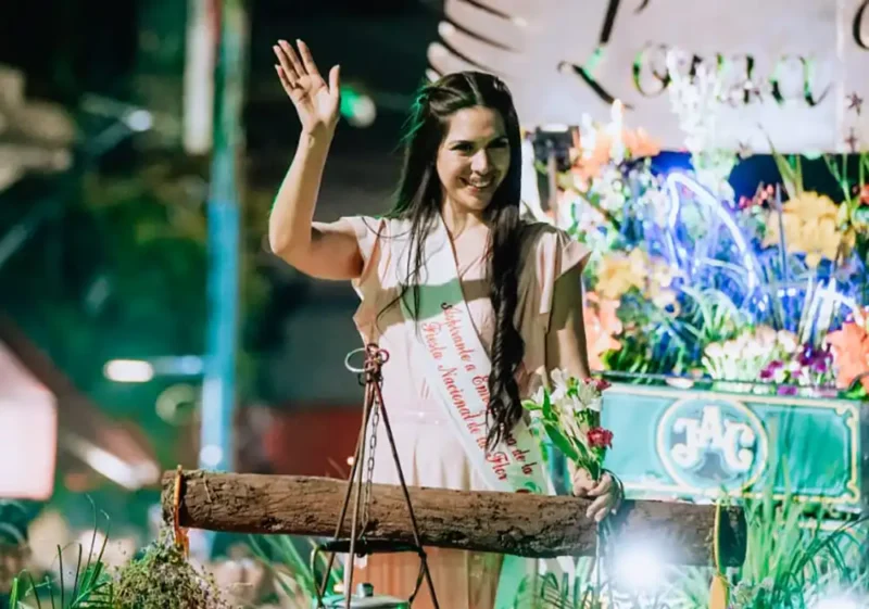 Embajadora de la Flor en una carroza saludando al público