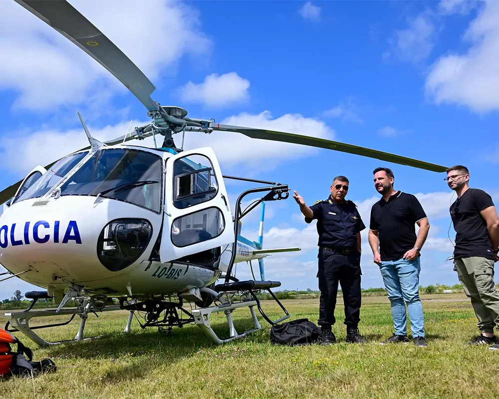 Ariel Sujarchuk junto a dos expositores ven detalles de un helicóptero