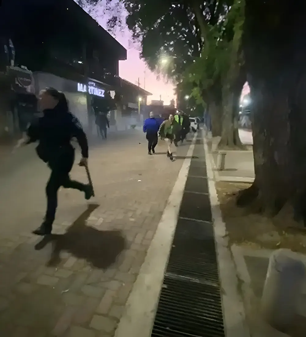 una mujer polic&iacute;a corre en medio de los disturbios en la calle Col&oacute;n