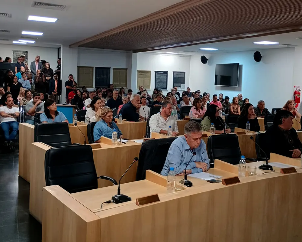 concejales en sus bancas y el público detrás de ellos