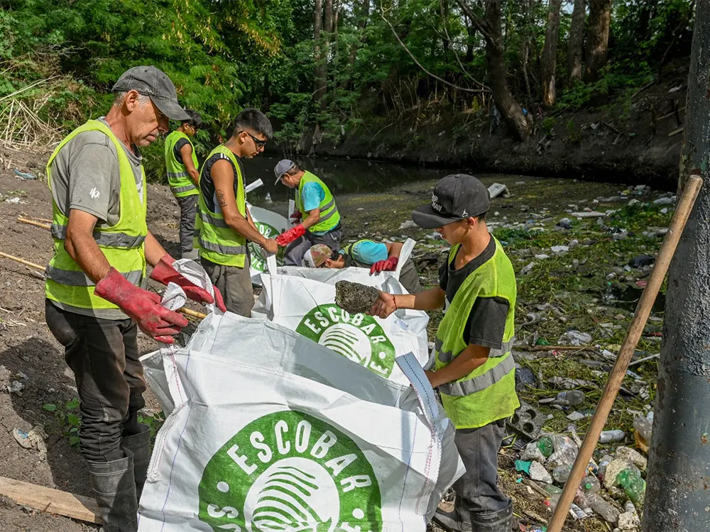 Voluntarios embolsando la basura que está flotando en el arroyo
