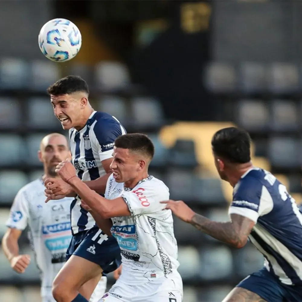 jugadores de Armenio y Talleres disputan una pelota aérea