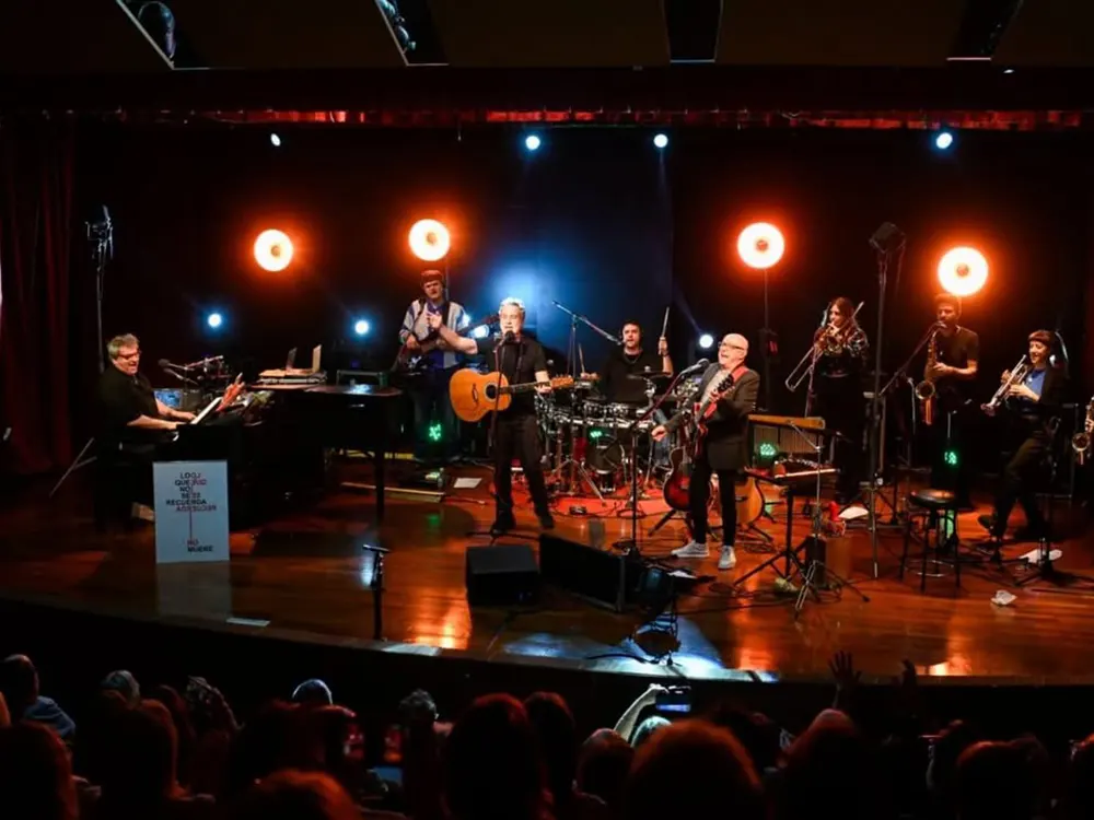 Baglietto y Vitale, acompañados de sus músicos, cantan en un escenario.
