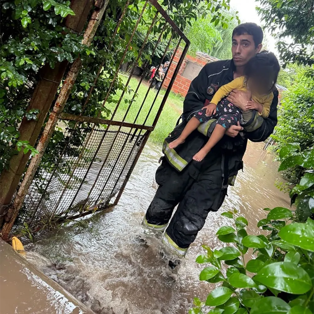un bombero lleva en sus brazos a una nena