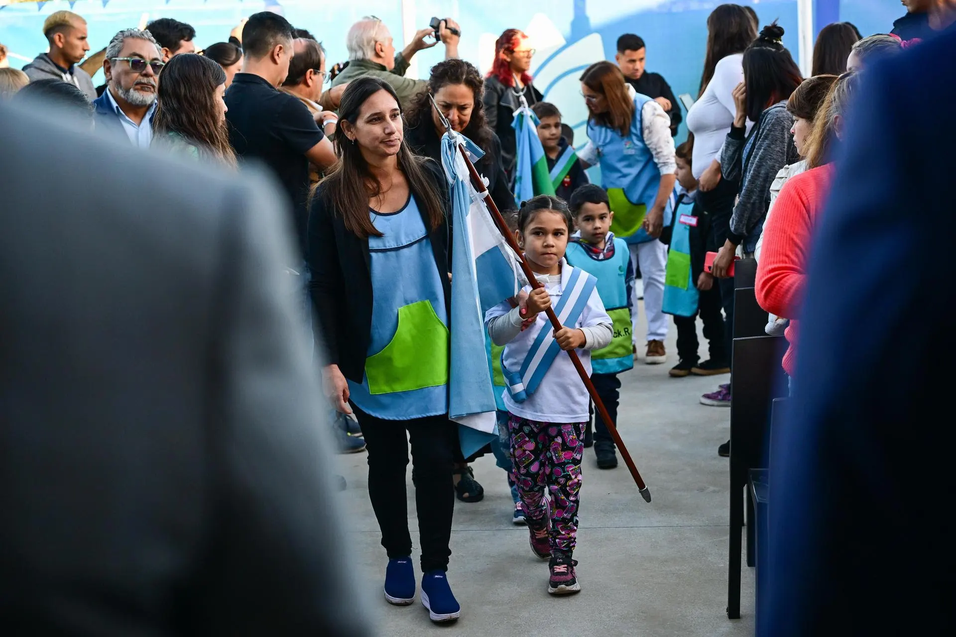 una maestra de jardín acompaña a una alumna abanderada