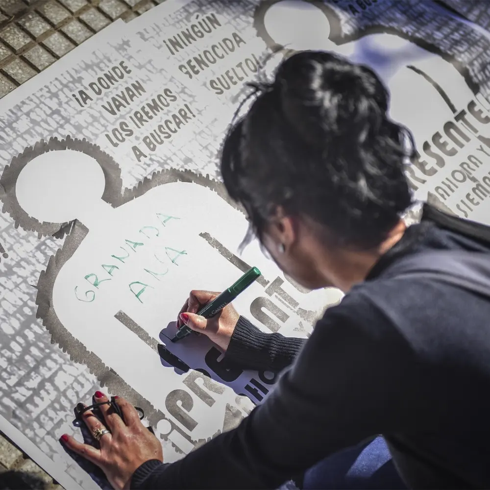 Mujer realiza un afiche en honor al día de la memoria, la verdad y la justicia.