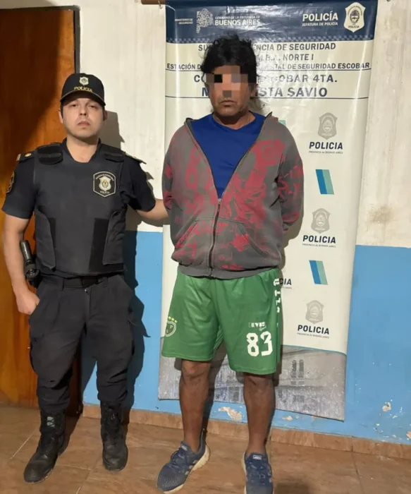Uno de los detenidos por el homicidio en Savio, con un policía al lado