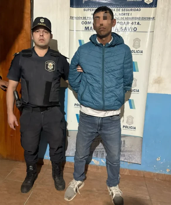 Uno de los detenidos por el homicidio en Savio, con un policía al lado