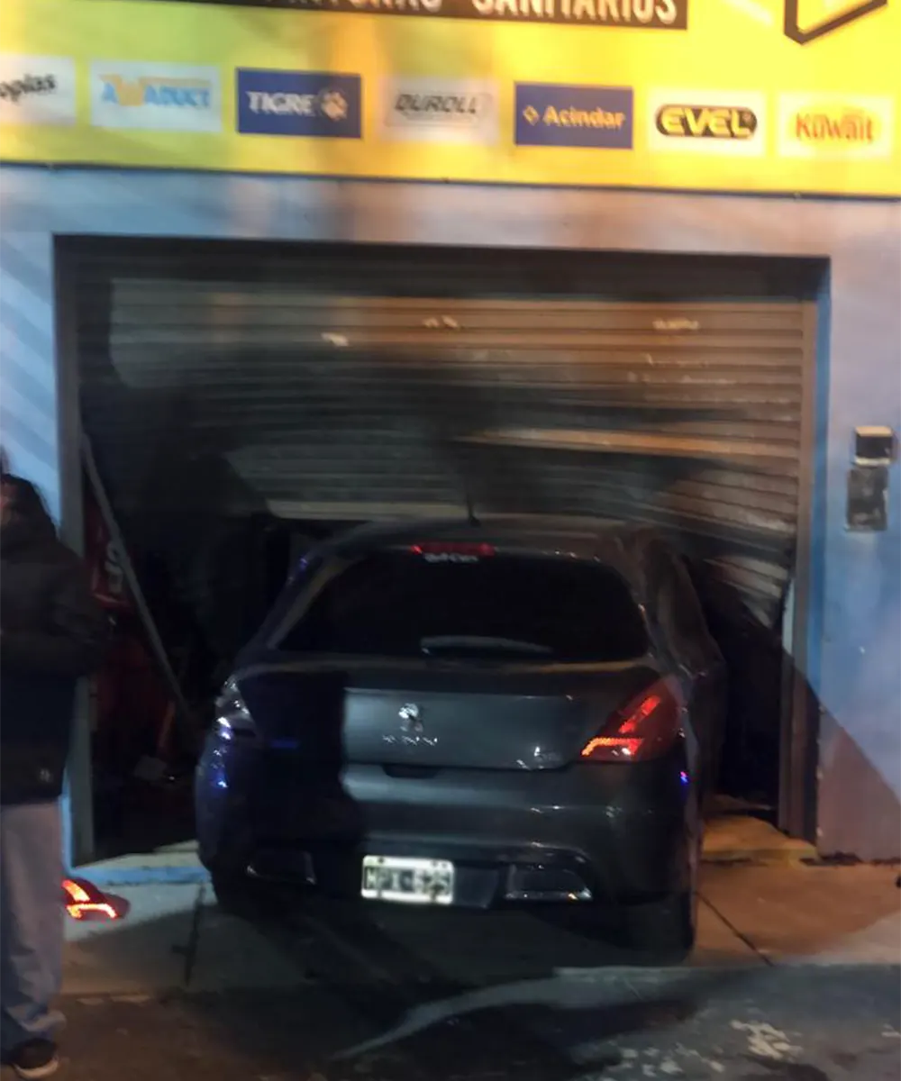 Auto incrustado contra la persiana del comercio