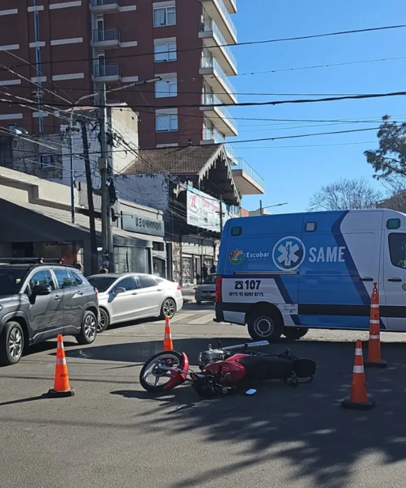 Moto tirada en el asfalto y ambulancia del SAME