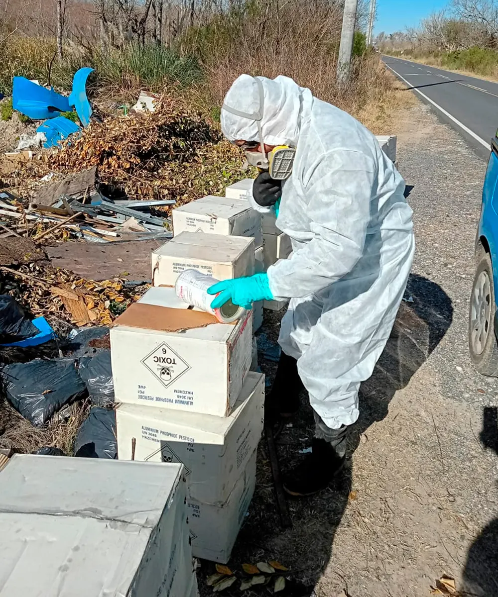 Un inspector con un traje de bioseguridad revisa las cajas al costado de la ruta 25