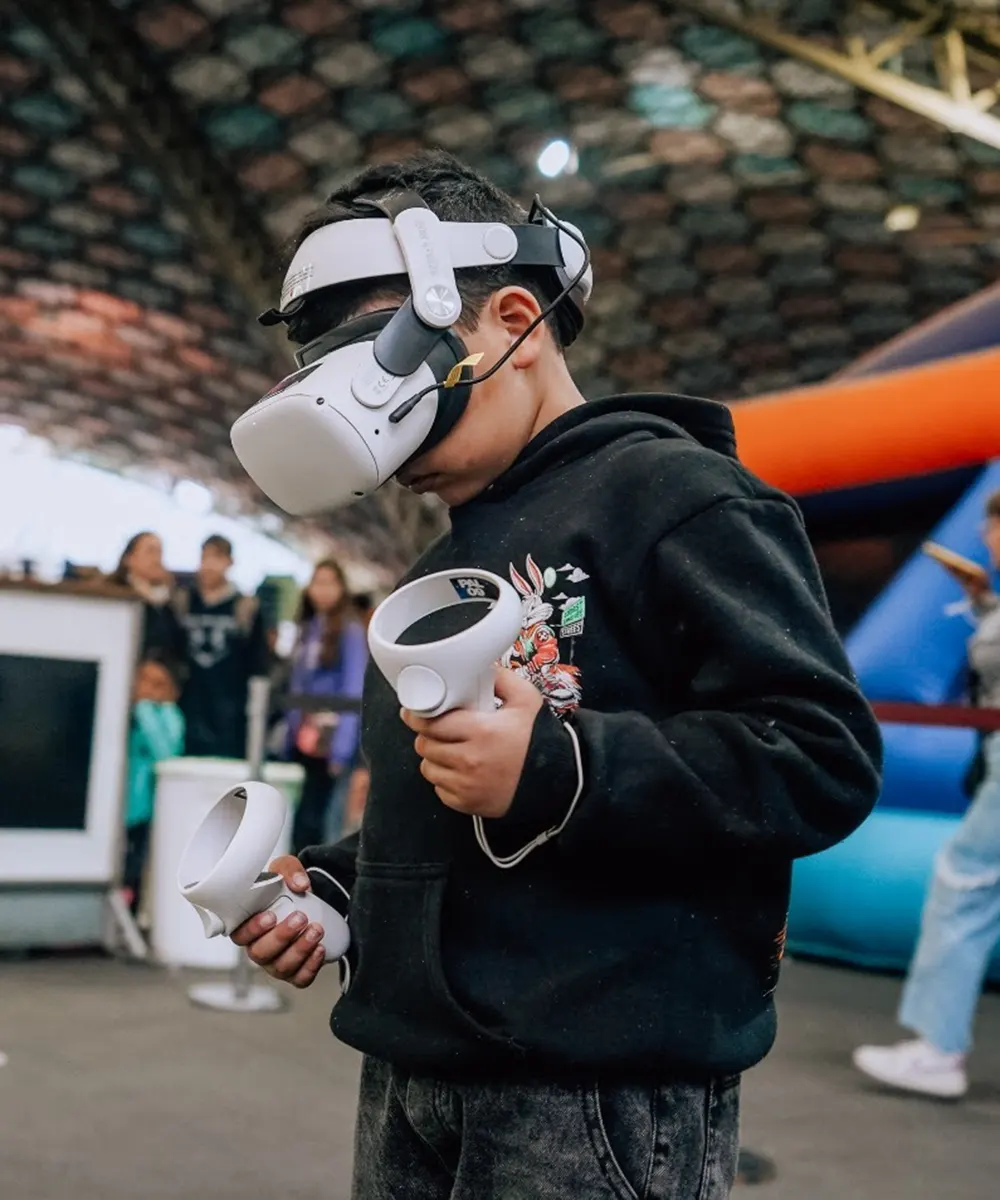 Niño con gafas de realidad virtual y controles en las manos disfrutando de la experiencia en el parque.