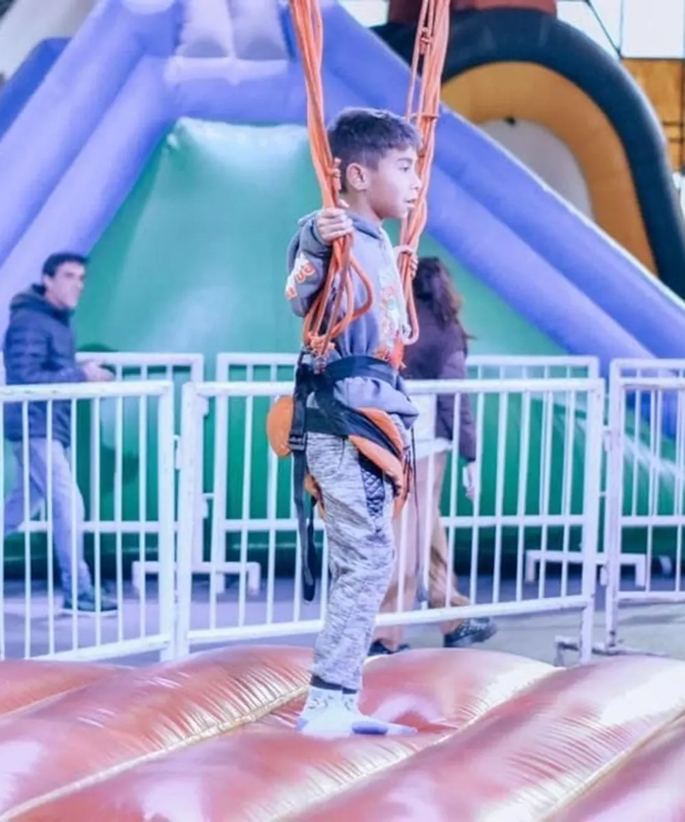 Niño con arnés de seguridad disfruta de un Bungee Inflable en Escopark.
