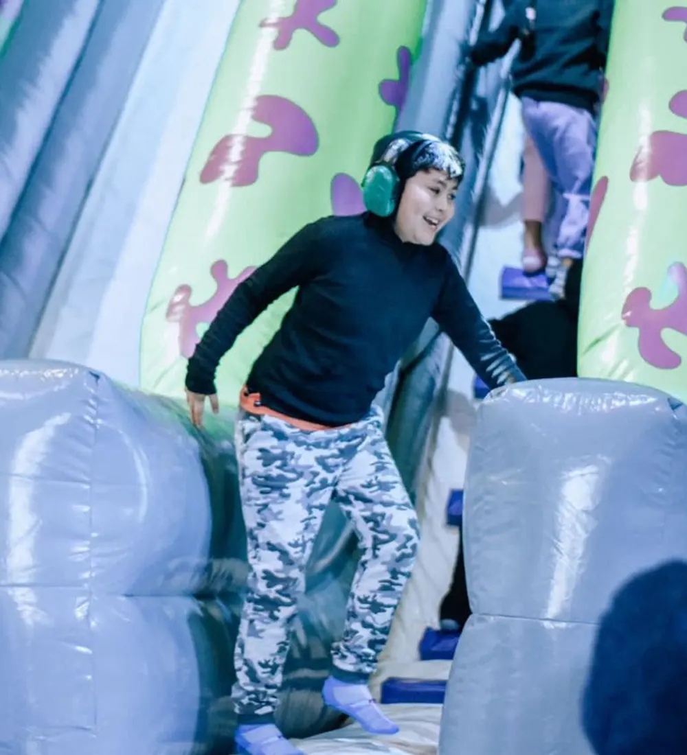 Niño con orejeras protectoras en una estructura inflable durante una jornada especial en el predio.