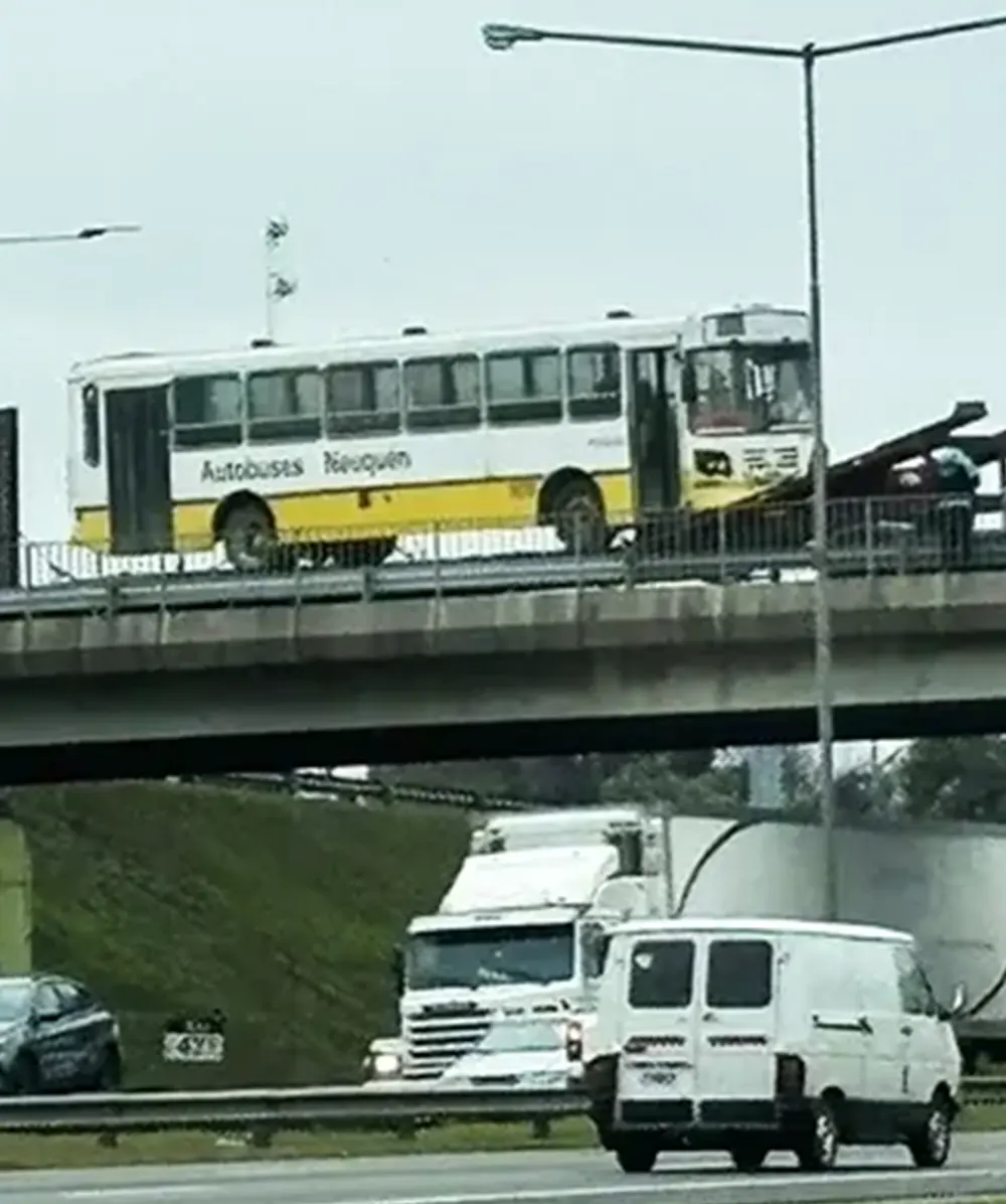 Colectivo parcialmente colgado sobre el Puente Septiembre, sostenido por un remolque.