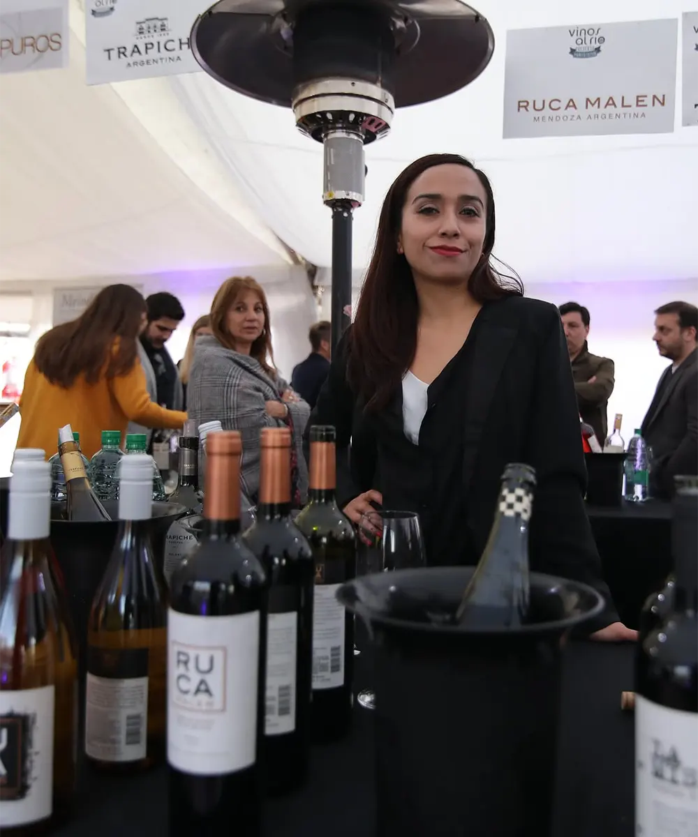 Botellas de vinos en una mesa y gente alrededor