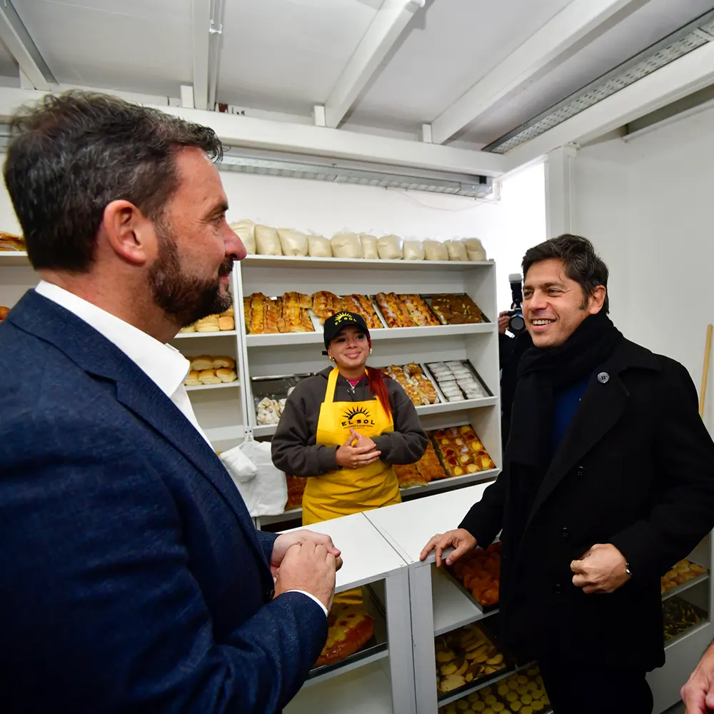El gobernador Axel Kicillof y el intendente Ariel Sujarchuk dialogan con una emprendedora local en su puesto de panificados del Mercado Bonaerense.