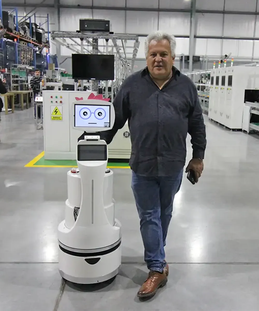 El fundador de Pixart con un robot en la planta de la empresa en Loma Verde