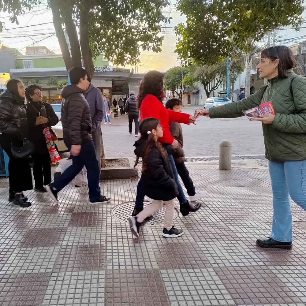 Romina Del Plá repartiendo volantes a la gente que pasa por la plaza de Escobar