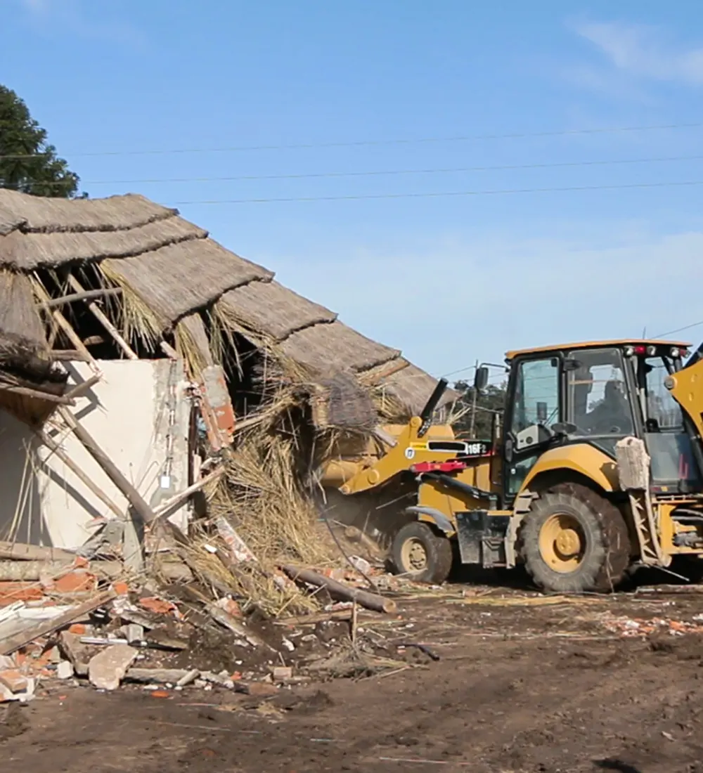 Una topadora derriba el quincho de una casa del predio usurpado y vendido por García.