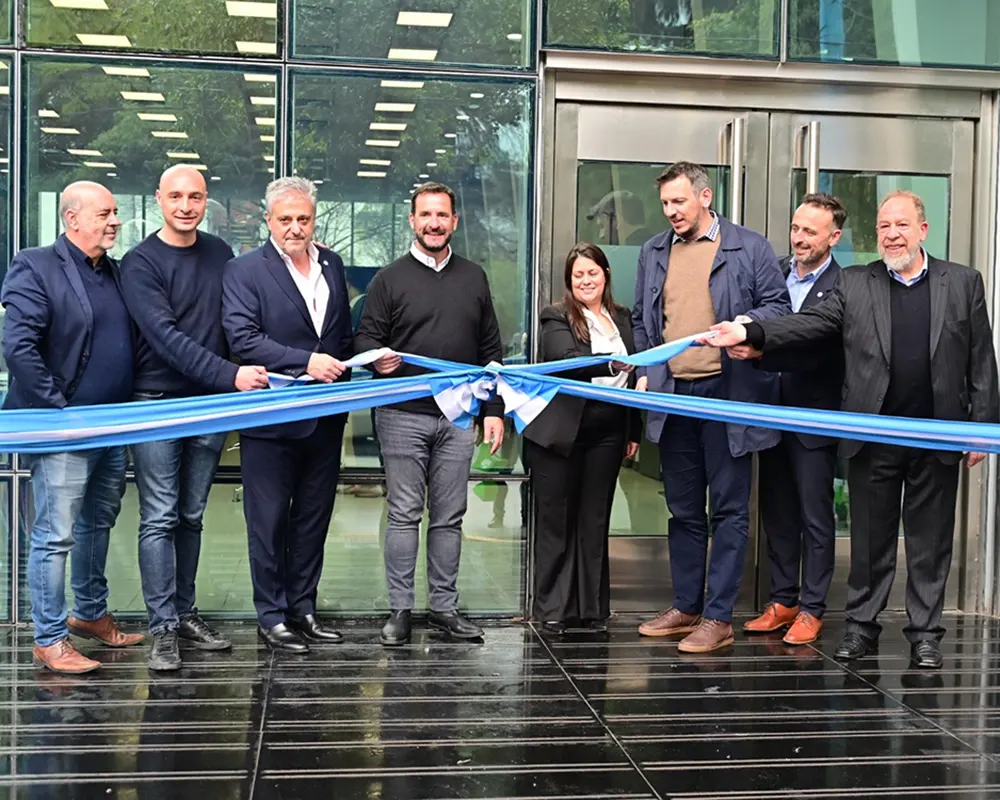Autoridades y empleados del Banco Provincia, junto con el presidente de la identidad bancaria, Juan Cuattromo y Ariel Sujarchuk, cortan un gran listón frente a las puertas de vidrio de la sucursal remodelada.