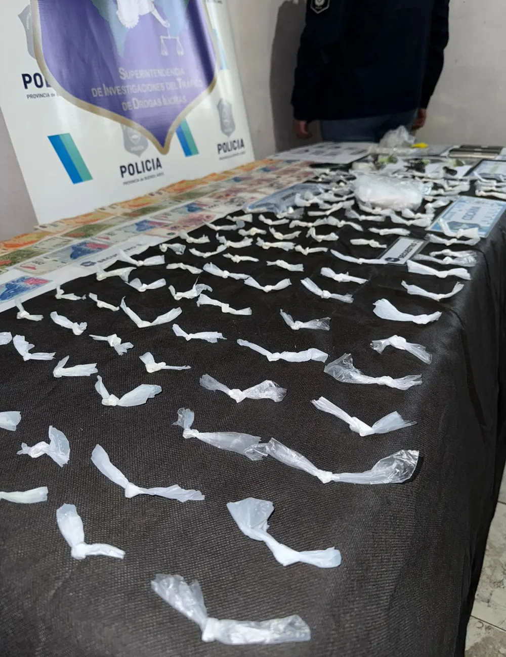 Plano de decenas de envoltorios de droga junto a billetes y pruebas secuestradas en el procedimiento policial en barrio Donatelli.