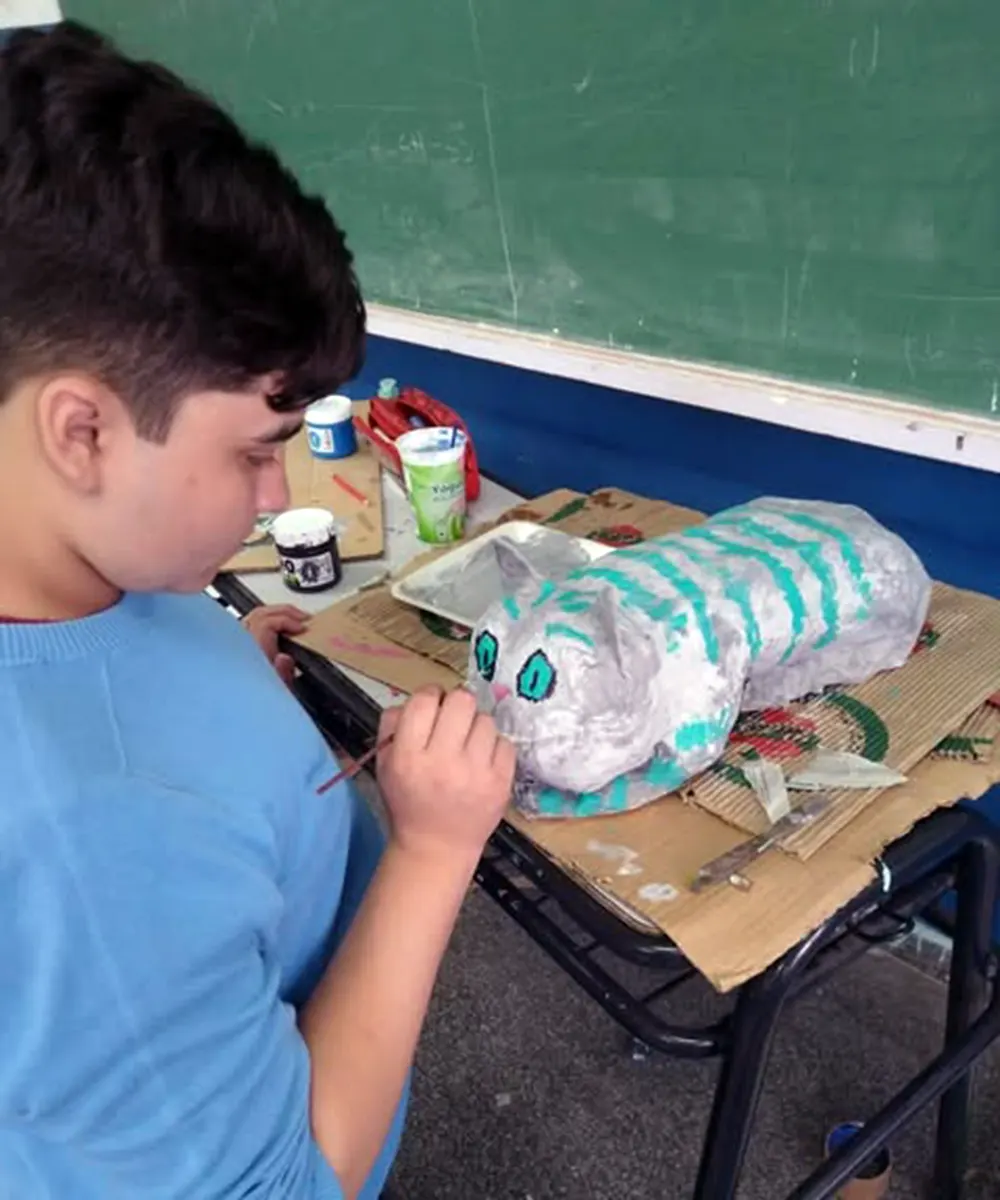 Alumno de la Escuela Secundaria Nº1 de Garín pintando al gato de la obra de Alicia el País de las Maravillas.