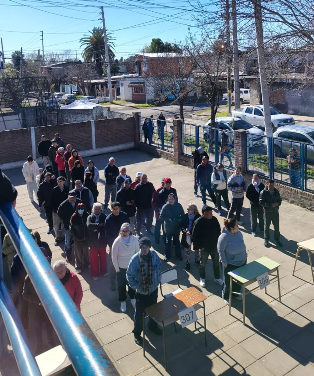 Gente haciendo la fila para votar en una escuela
