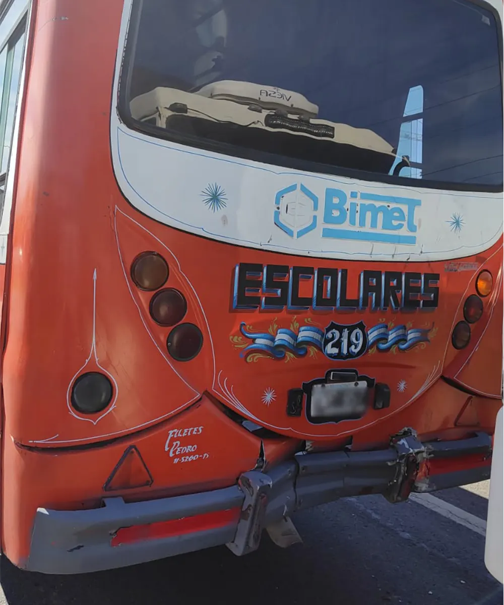 Transporte escolar marca Mercedes Benz, abollado en la parte de atrás por el choque