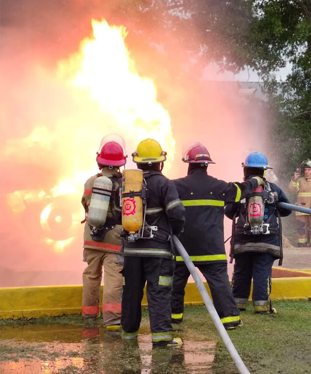 Bomberos apagan el fuego durante una de las prácticas del entrenamiento.