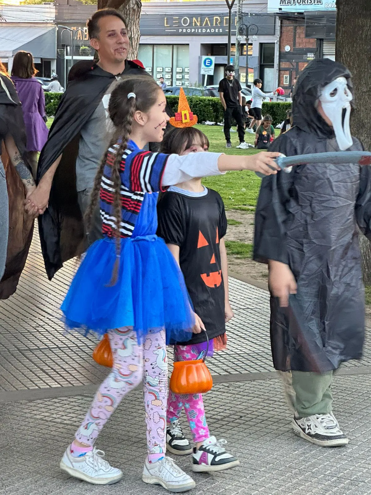Tres niños disfrazados en el centro de la plaza San Martín de Belén de Escobar.