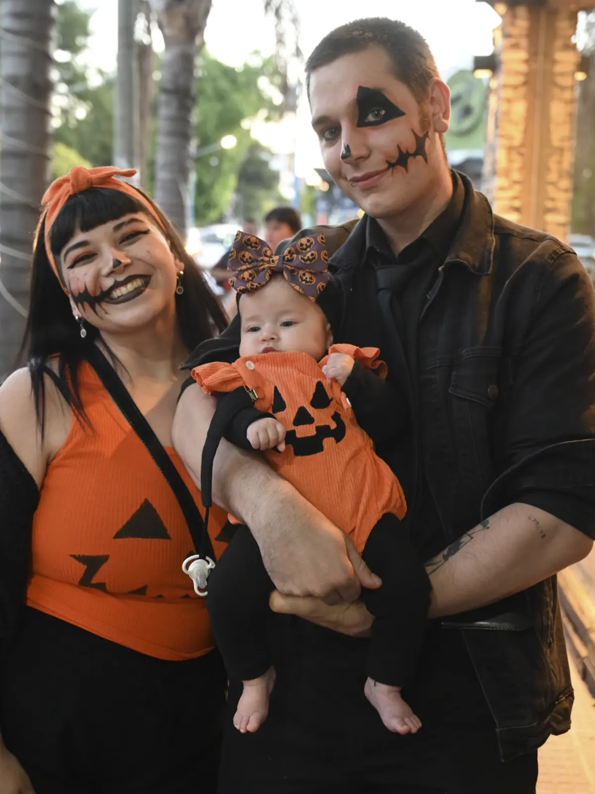 famila carga en brazoz a su hijo desfrazado de calabaza