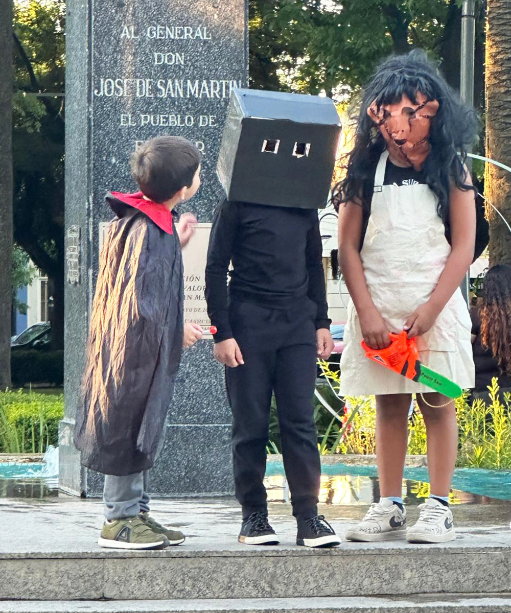 Tres niños disfrazados en el centro de la plaza San Martín de Belén de Escobar.