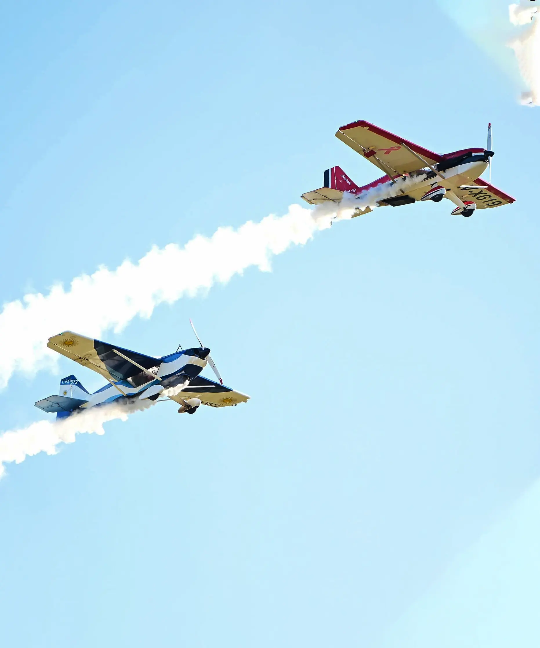Dos avionetas, vuelan de manera paralela formando líneas en el cielo.