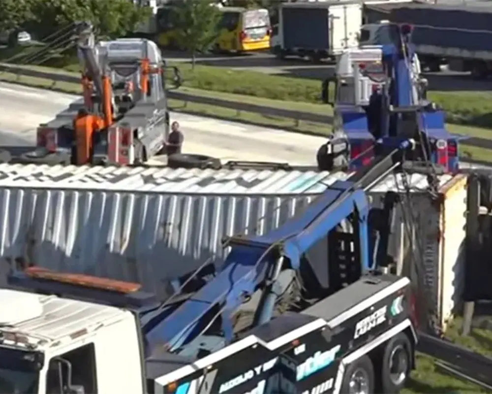 Tres grúas levantando el camión y su acoplado.