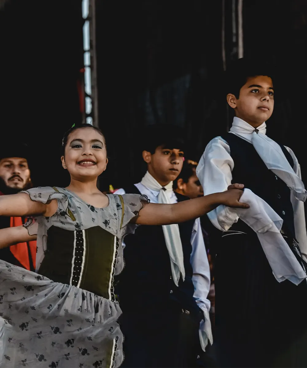 Niños con vestimenta típica en el festival de raíces provinciales.