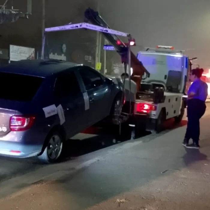 Personal de tr&aacute;nsito junto al auto remolcado 