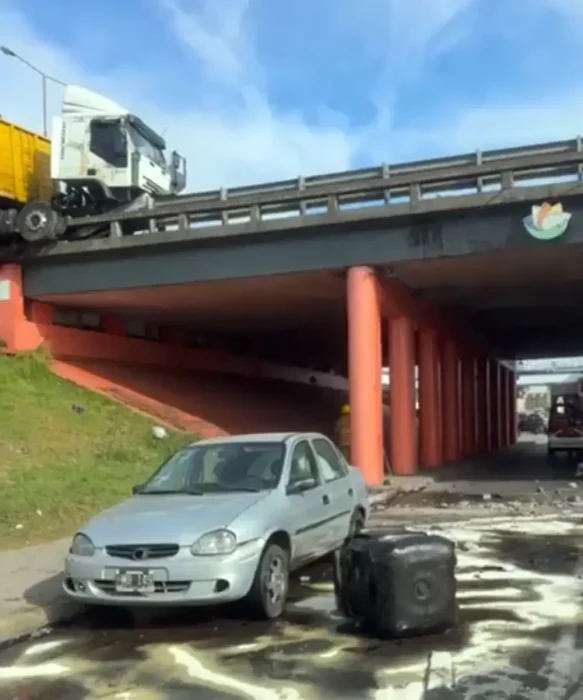 parte del cami&oacute;n suspendida en el aire arriba del puente y el tanque de combustible desprendido sobre la avenida