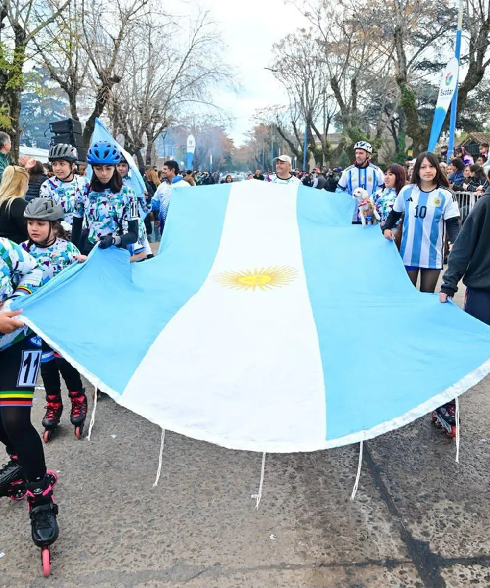 Equipo de pat&iacute;n desfilando con la bandera de argentina