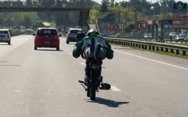 un motociclista que circula completamente recostado sobre el asiento