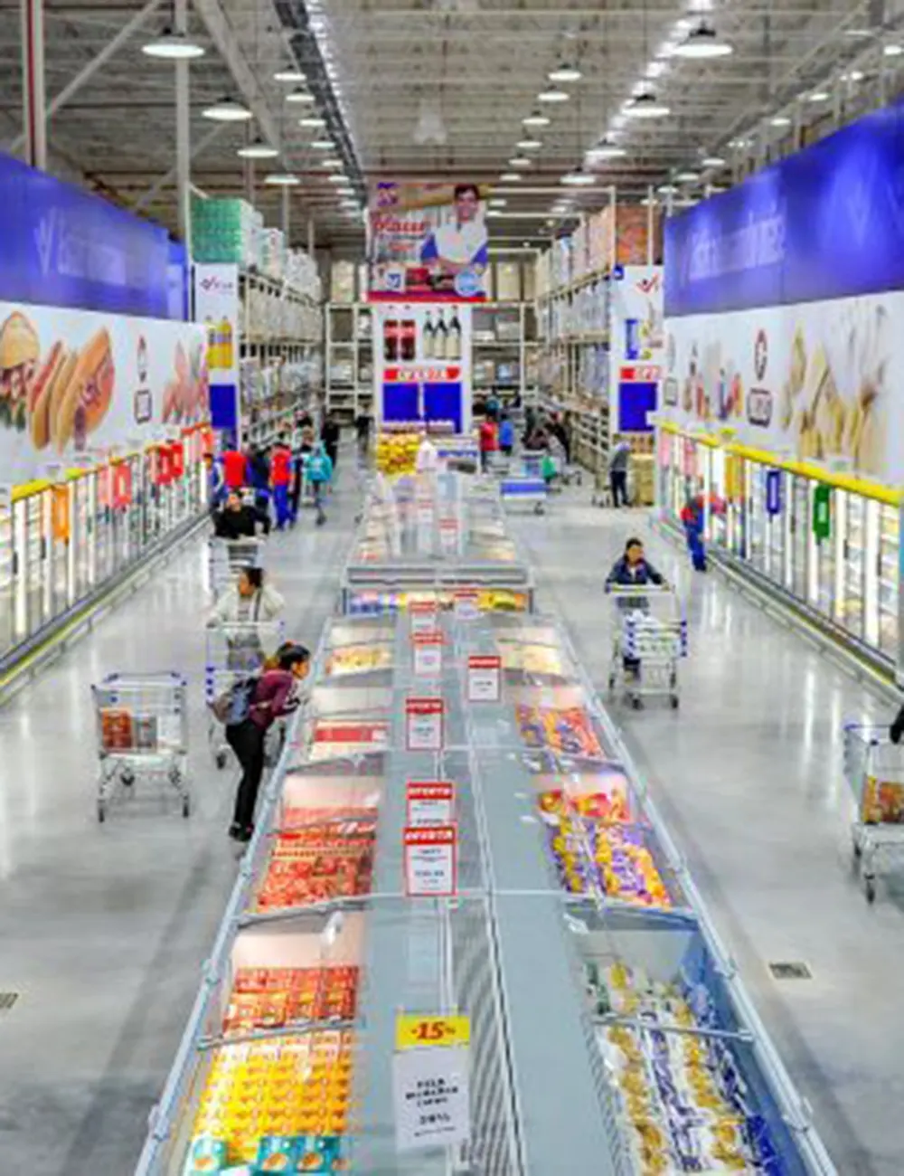 Pasillos con gente y heladeras en Supermercado Vital.
